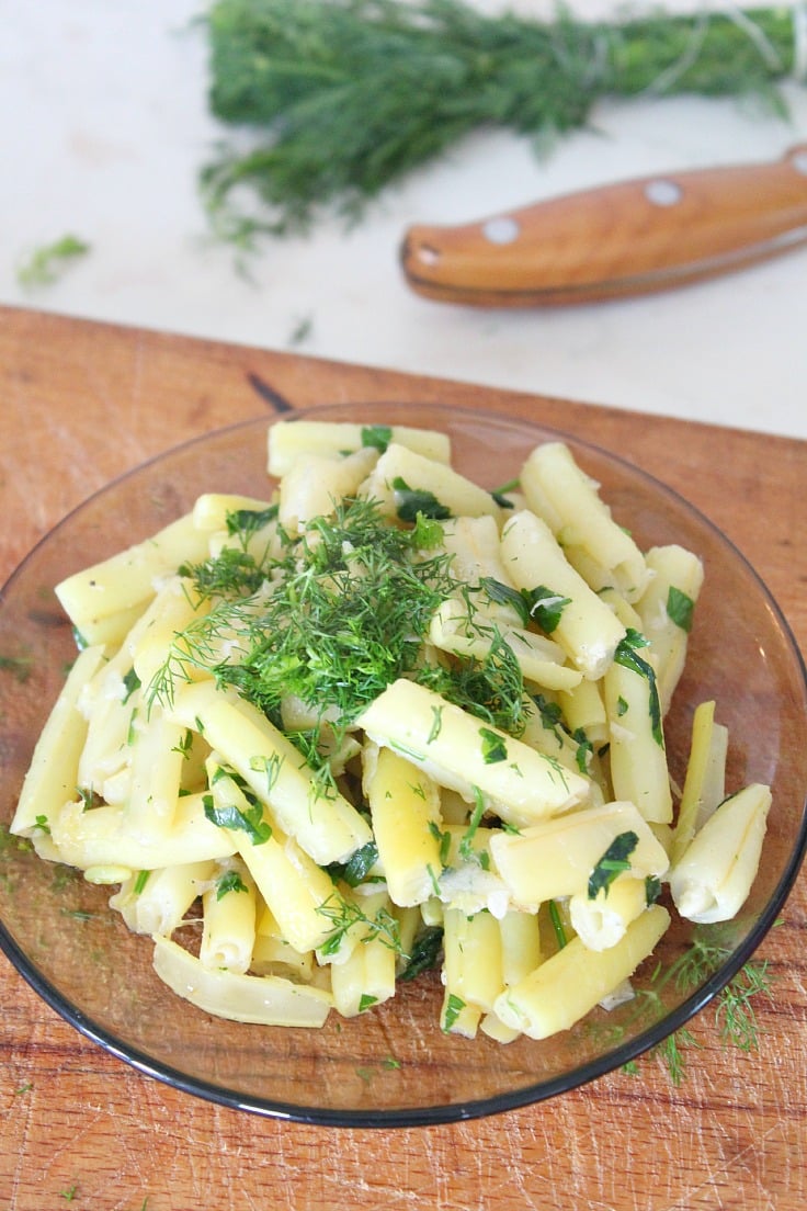 Yellow beans with garlic and dill, served on a brown plate