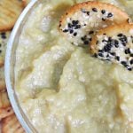 Eggplant dip in a bowl with mixed seed crackers