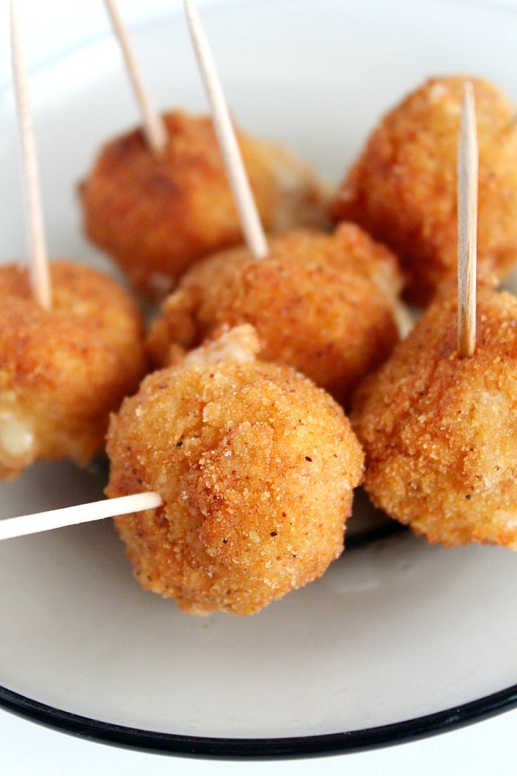 Spicy fried cheese balls on a white plate, with toothpicks for easy serving