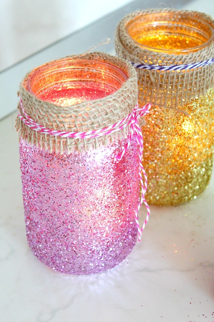 Mason Jar Luminaries made out of jars painted in mod podge and glitter and decorated with twine ribbon and bakers twine around the neck