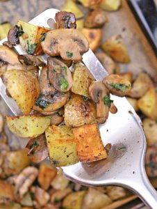 Roasted potatoes and mushrooms with garlic and fresh parsley in a baking sheet
