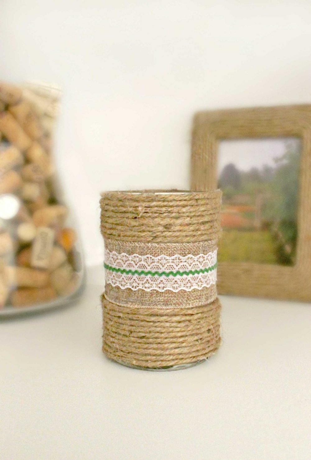 Decorated candles, with burlap ribbon and ric rac in the middle and rows of twine at the bottom and the top