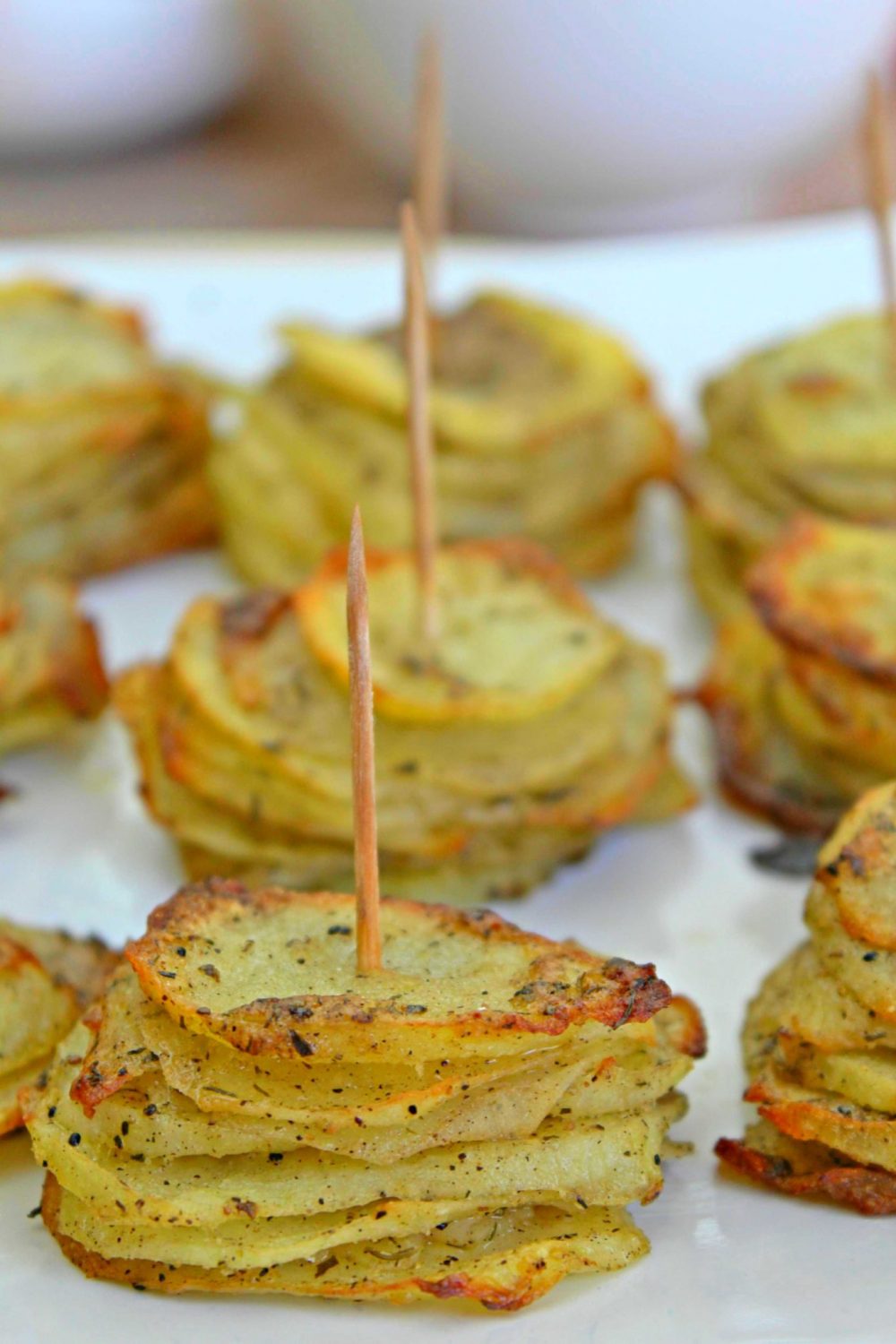 Parmesan potato stacks with garlic and herbs on a white serving plate