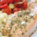Lemon herb salmon with roasted vegetables and couscous on a white serving plate