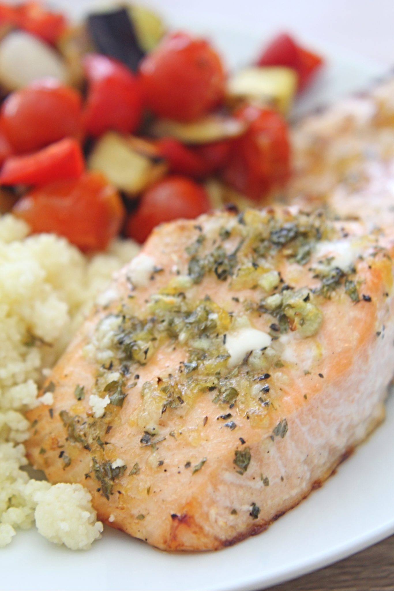 Lemon herb salmon with roasted vegetables and couscous on a white serving plate