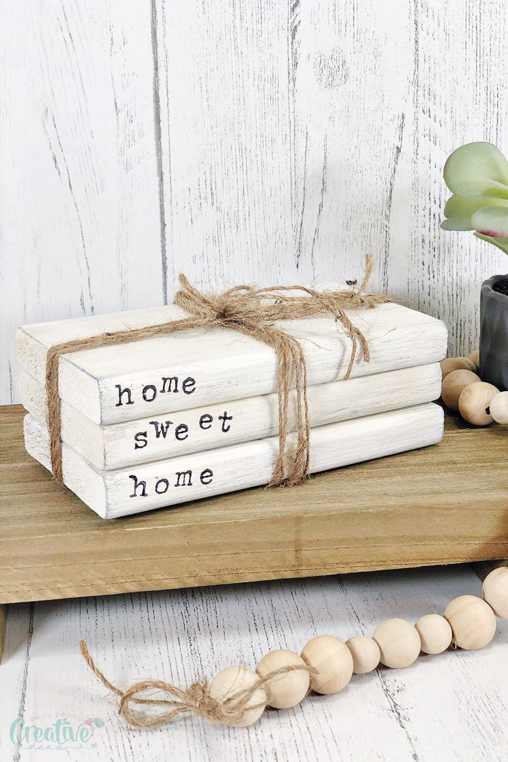 Image of fake stack of books made with wood, stamped letters and twine