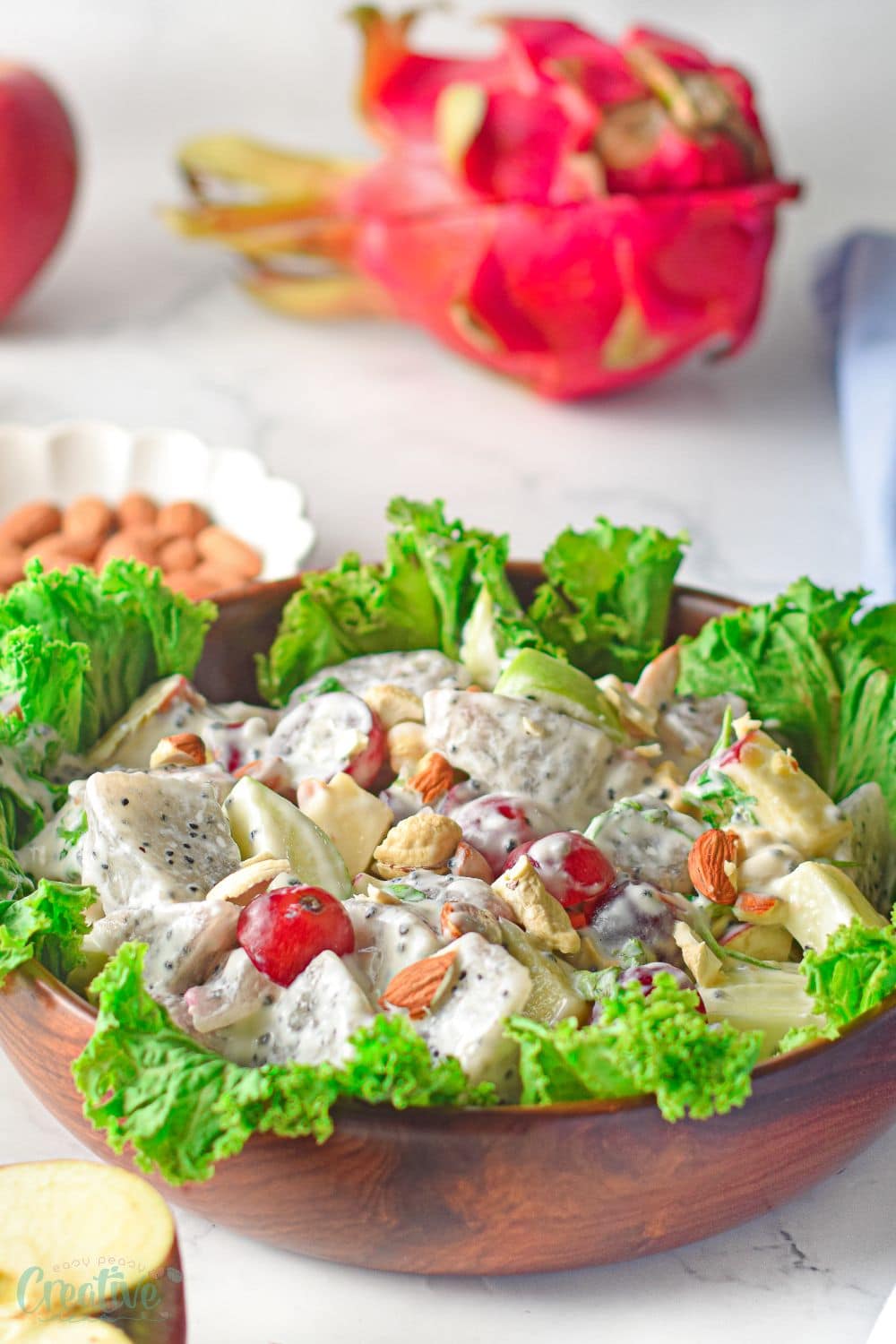 Close up image of modern Waldorf salad prepared with dragon fruit and displayed on a bed of lettuce, in a brown salad bowl