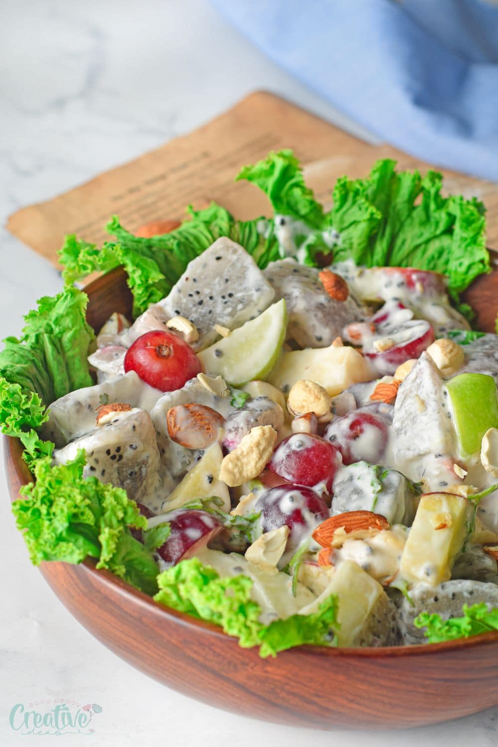 Close up image of Waldorf salad ingredients on a lettuce bed, in a brown salad bowl