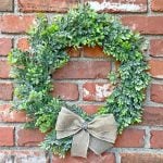 Close up image of farmhouse Christmas wreath made with fake boxwood and a bow