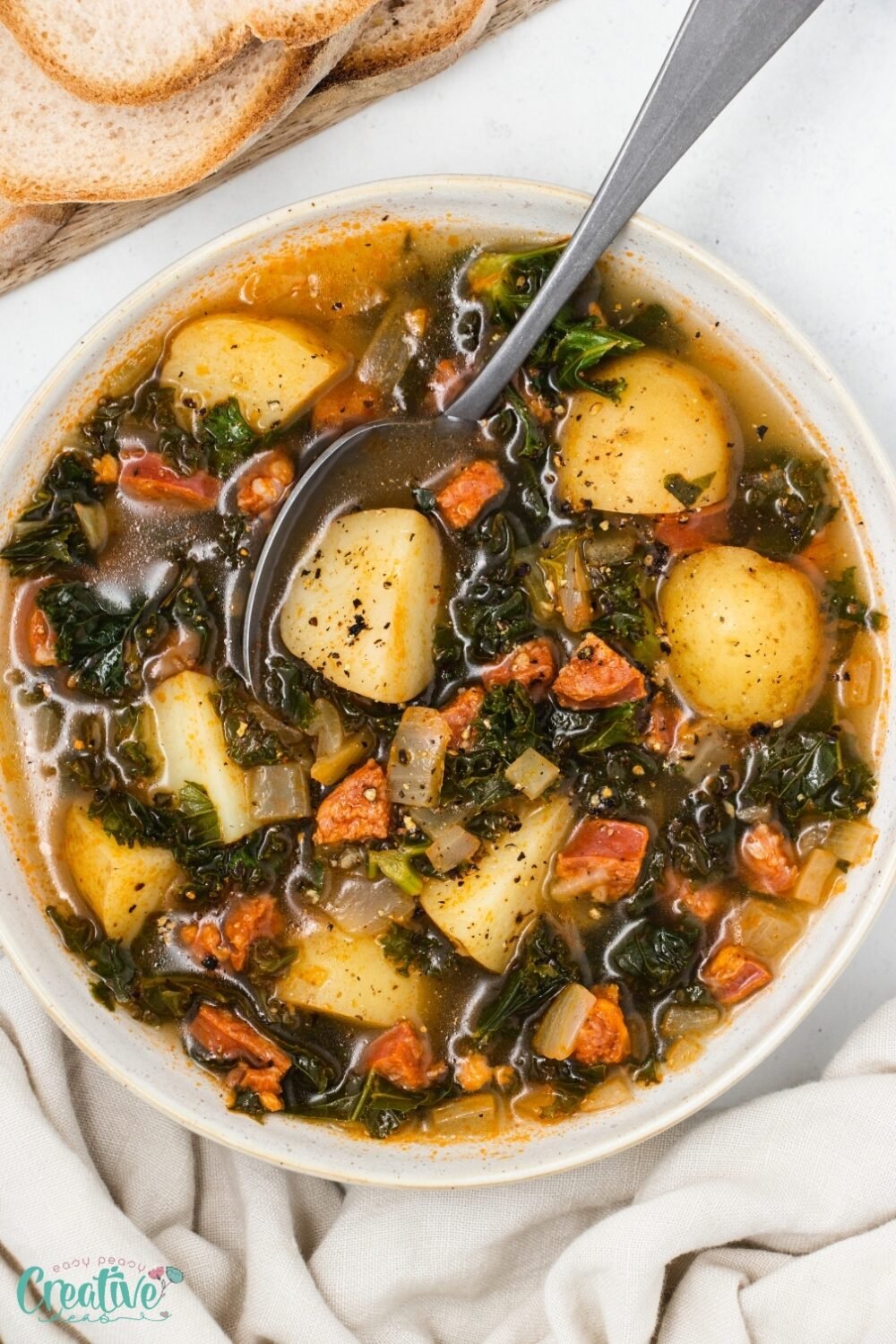 A bowl of chorizo and kale soup with potatoes, chorizo, and kale, served hot and garnished with fresh herbs.