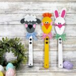 Three decorated wooden spoons with cute Easter animals painted on them - a bunny, a chick, and a lamb.