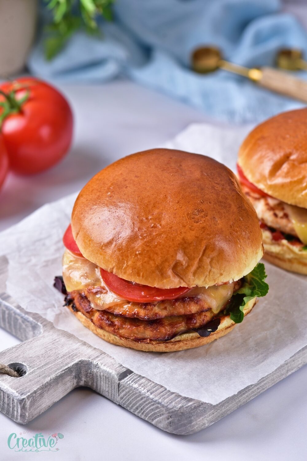 Delicious oven baked turkey burgers with lettuce and tomatoes resting on a cutting board, ready to serve.